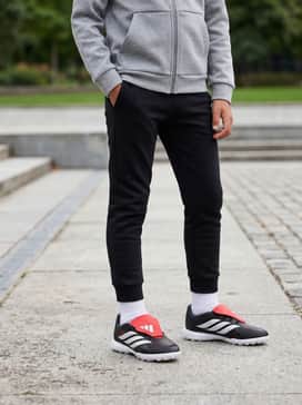 Predator League Foldover Tongue Turf Soccer Shoes Kids – Slim-fit black joggers and a grey tech-fleece hoodie, creating a sleek streetwear-inspired athletic outfit for cool-weather training.