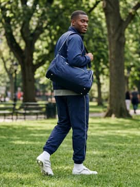 For travel to the pitch, a sleek navy blue track suit with white piping details and a matching athletic duffel bag for a coordinated team appearance.