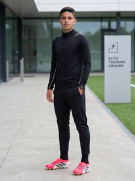 A sleek, black aerodynamic training top with neon yellow piping, paired with matching tapered track pants and a lightweight performance headband.