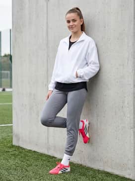 Predator Pro Foldover Tongue Artificial Ground Soccer Cleats – A crisp white quarter-zip windbreaker worn over a breathable mesh tank top, styled with grey athletic leggings for cold-weather training sessions.