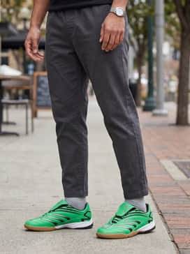 Medium-wash straight-leg denim jeans with a slight cuff at the ankle, worn with a black vintage-style nylon windbreaker for a sleek 90s athletic vibe.