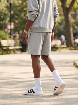 A cozy lounge set with heather grey sweatshorts, a matching oversized hoodie, and thick white athletic socks for maximum comfort while maintaining a stylish silhouette.