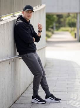 Questar 3 Running Shoes – Charcoal grey fleece sweatpants matched with a coordinated oversized black hoodie and a structured baseball cap for a relaxed, urban aesthetic.