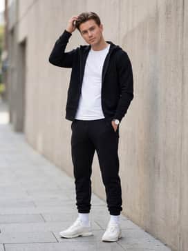 Black tech-fleece joggers, a slim-fit white performance tee, and a matching zip-up hoodie for a sleek, monochromatic athleisure ensemble.