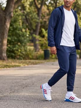 Style with slim-fit navy joggers and a crisp white cotton tee, layered under a lightweight blue windbreaker for a polished athleisure aesthetic.