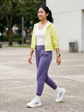 High-waisted purple compression leggings paired with a white moisture-wicking racerback tank and a cropped neon yellow windbreaker.