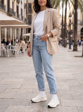 Light-wash tapered denim jeans worn with a tucked-in white organic cotton tee and a beige oversized blazer for a polished 'clean girl' street style.