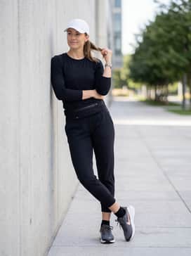 Tapered black joggers and a matching slim-fit performance long-sleeve top, accessorized with a sleek running belt and a white baseball cap for a focused athletic aesthetic.
