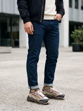 Dark wash slim-fit denim jeans with a tucked-in cream mock-neck sweater and a black bomber jacket to let the sneaker's complex colors stand out.