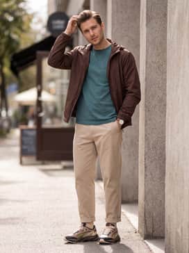 Rs Surge Las Vegas Mens Sneakers – Relaxed-fit beige chinos coupled with a teal-colored pocket t-shirt and a lightweight chocolate brown windbreaker for a coordinated, earthy aesthetic.