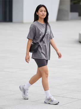 High-waisted charcoal biker shorts paired with an oversized vintage graphic t-shirt, slouchy white crew socks, and a sleek crossbody bag.