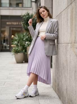 Rs Surge Nyc Womens Sneakers – A pastel lavender pleated midi skirt teamed with a fitted cream-colored turtleneck and a structured grey blazer for a high-low fashion contrast.