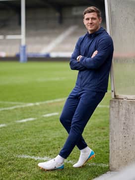 Rs15 Elite Sg Shoes – A pre-match warmup look featuring a lightweight navy blue windbreaker and tapered athletic track pants.
