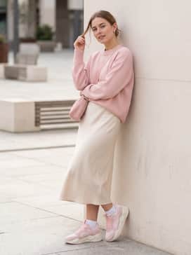 A white tennis skirt combined with a pastel pink oversized sweater and a matching pink crossbody bag.
