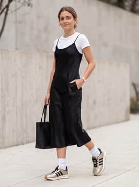 A black satin midi slip dress layered over a slim-fit white baby tee to create a chic 90s-inspired streetwear aesthetic.