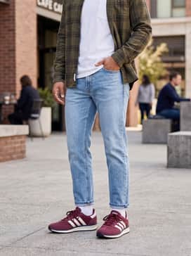 Run 70s 20 Shoes – Straight-leg light-wash denim jeans and a simple white pocket tee, topped with an unbuttoned olive flannel shirt.