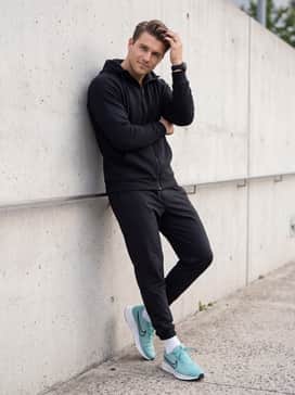 Run Defy – A modern athleisure outfit consisting of tapered black joggers, a white performance zip-up hoodie, and a technical sports watch for a sleek, functional aesthetic.