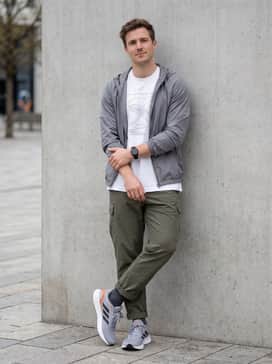 Technical olive green cargo pants, an oversized white graphic t-shirt, and a lightweight grey windbreaker for a functional urban streetwear vibe.