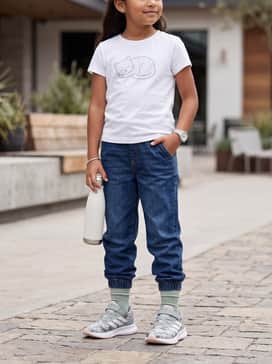 Runfalcon 5 Shoes Children – Dark wash denim joggers tucked slightly at the ankle, worn with a white graphic t-shirt featuring a cute animal print to complement the shoe pattern.