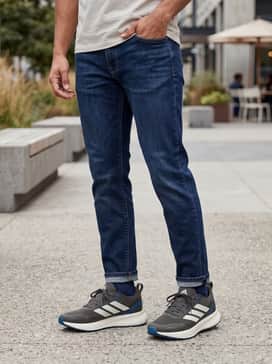 Dark-wash tapered jeans paired with a crisp white crewneck t-shirt and a navy blue zip-up hoodie for a clean, relaxed weekend look.