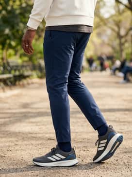 Slim-fit navy track pants and a structured off-white sweatshirt that coordinates with the creamy midsole for a cohesive athleisure aesthetic.