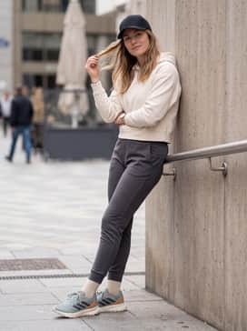 Slim-fit charcoal joggers with a cropped cream-colored hoodie and a sleek black baseball cap for a coordinated streetwear aesthetic.
