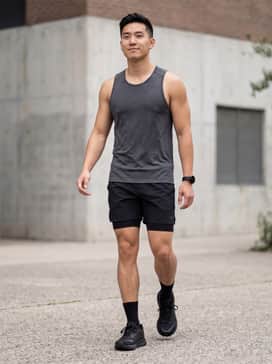 Performance-focused look featuring black moisture-wicking compression shorts, a charcoal grey tech-fabric tank top, and low-cut black athletic socks.