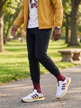 S2g 26 Textile Spikeless Golf Shoes – A streetwear-inspired set consisting of tapered black joggers, a graphic white t-shirt, and a lightweight mustard-yellow windbreaker.