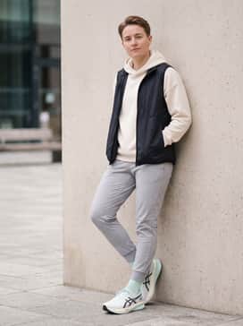 A casual weekend outfit consisting of slim-fit light wash denim, a cream-colored hoodie, and a navy nylon bomber jacket for a layered look.