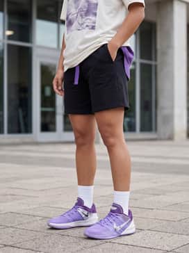Sabrina 3 Flowers – Casual streetwear ensemble consisting of black biker shorts, an oversized off-white graphic tee, and a matching purple baseball cap for a balanced off-court look.