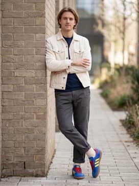 Off-white corduroy trousers combined with a navy blue knit polo shirt for a smart-casual look that lets the primary colors of the shoes pop.