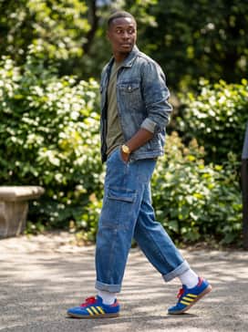 Wide-leg cargo pants in olive green, a vintage graphic band tee, and a denim jacket for a textured, streetwear-inspired ensemble.