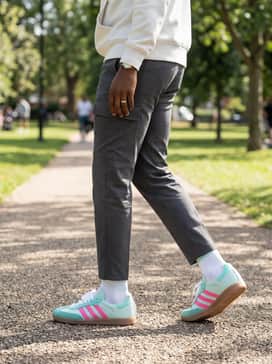 Samba Messi Shoes – Charcoal gray cargo pants and a neutral white hoodie to provide a muted canvas that allows the vibrant shoe colors to stand out.