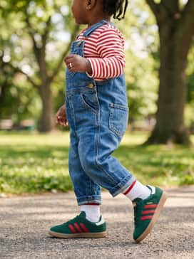 Denim overalls worn over a red-and-white striped long-sleeve shirt to lean into the vintage sporty vibes of the Samba silhouette.