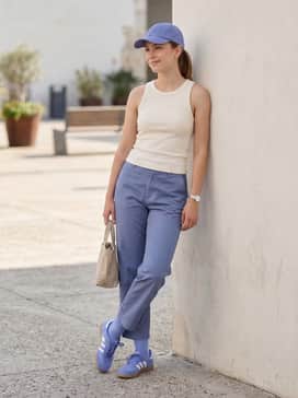 Tan cargo pants worn with a tight-fitting cream ribbed tank top and a periwinkle baseball cap to coordinate with the footwear.
