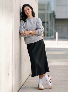 A black satin midi skirt paired with an oversized grey sweatshirt and white crew socks to lean into the popular 'clean girl' aesthetic.