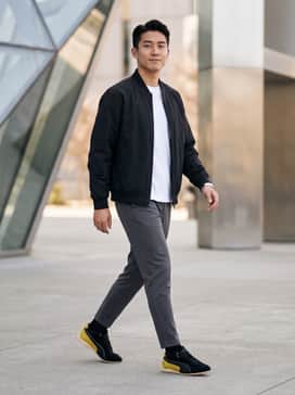 Slim-fit black selvedge jeans paired with a crisp white heavyweight t-shirt and a black nylon bomber jacket for a sleek, monochromatic urban look.