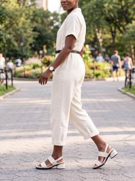 A monochromatic cream-colored jumpsuit with a thin black belt to echo the shoe's sole and create a streamlined silhouette.