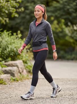 Seasons Explore Nitro – A pair of black high-waisted compression leggings matched with a charcoal moisture-wicking quarter-zip and a coral-colored headband.