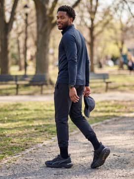 A cold-weather training set including thermal compression leggings under dark navy athletic shorts and a quarter-zip moisture-management pullover.
