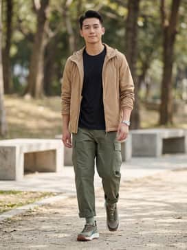 A pair of olive green ripstop cargo trousers paired with a black moisture-wicking technical t-shirt and a lightweight tan windbreaker for a functional outdoor look.