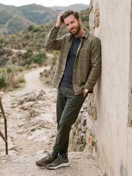 Slim-fit dark wash denim jeans coupled with a beige flannel shirt layered over a grey thermal henley for a rugged yet casual weekend outfit.