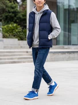 Session – A pair of tapered dark wash denim jeans rolled at the cuff, paired with a heather grey hoodie and a navy blue puffer vest for a layered, cool-weather school look.