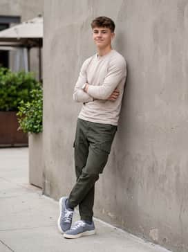 Black cargo trousers with a tucked-in olive green long-sleeve tee and a neutral-toned utility vest for an urban explorer vibe.