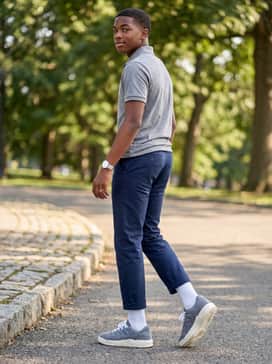 Navy blue chino shorts worn with white crew-length socks and a classic grey heather polo shirt for a clean, preppy aesthetic.