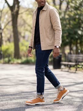 Session Se – Dark indigo tapered jeans paired with a black mock-neck long-sleeve shirt and a structured beige chore coat for a refined yet laid-back urban aesthetic.
