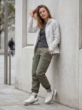 Sgendo Trail Shoes – Olive green ripstop cargo pants with adjustable cinch cords at the ankles, paired with a translucent white weather-resistant shell and a black thermal base layer.