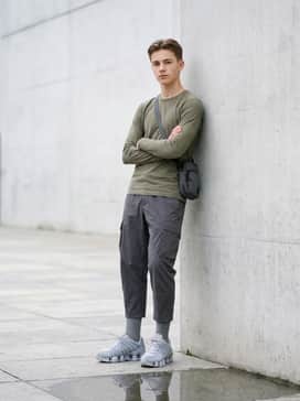 Loose-fitting cargo pants in olive green and a fitted white long-sleeve tee, topped with a utility crossbody bag.