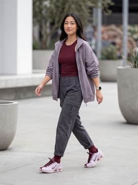 High-waisted charcoal cargo pants paired with a cropped burgundy rib-knit tank top and an oversized technical windbreaker for a rugged yet feminine street look.