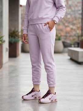 A monochrome lavender sweatsuit set consisting of tapered joggers and a zip-up hoodie, layered over a crisp white baby tee to emphasize the shoe's primary hue.